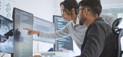 Two engineers reviewing code together at their workstations